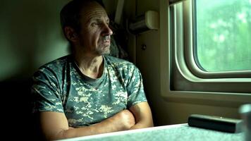 Thoughtful man riding in a train carriage and looking out the window video