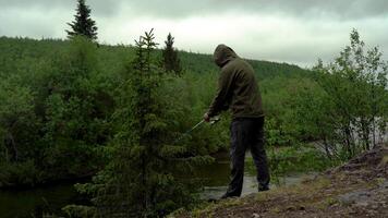 A fisherman caught a fish from a river while standing on a rock video