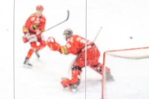 blurred view through protective glass. hockey player on the ice surface of the stadium photo