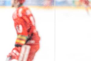 blurred view through protective glass. hockey player on the ice surface of the stadium photo