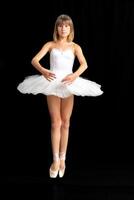 portrait of a teenage ballerina in a suit on a black background photo
