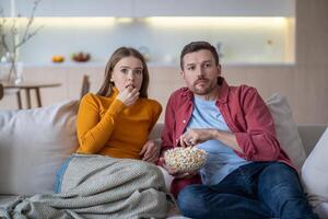 Surprised couple amazed by sudden turn of events in film, show, program while watching TV at home photo