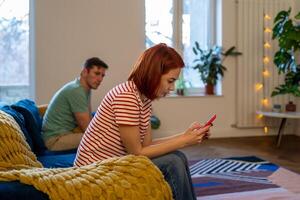 Toxic relationship. Couple sits on couch after quarrel. Girl writes support from domestic violence photo