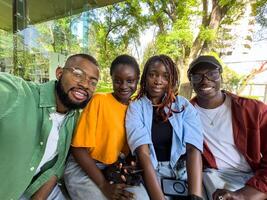 Four black student friends take selfie take break from studying while sit outside university library photo