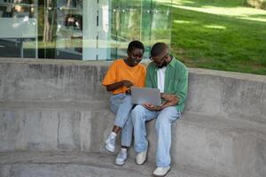 Thoughtful boyfriend, girlfriend classmates using computer to study sitting on campus stairs outside photo
