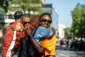 Joyful black students in good mood hugging each other in friendly warmly way on street outside. photo