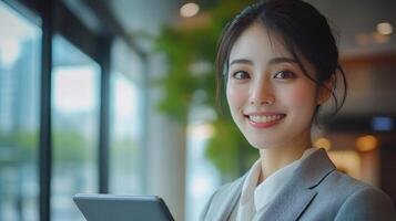 Asian woman with a tablet in her hand is smiling photo
