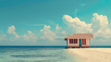 A vibrant beach house stands alone by the serene ocean under fluffy clouds photo