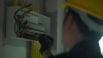 Electrician using electric screwdriver tester to check electric current in control box in home electrical installation and safety concept video