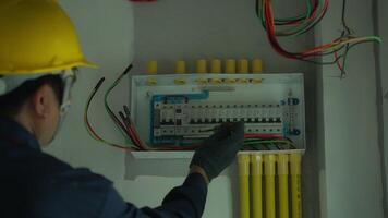 Electrician using electric screwdriver tester to check electric current in control box in home electrical installation and safety concept video