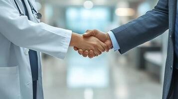 A doctor and a businessman shake hands in a hospital setting, signifying collaboration photo