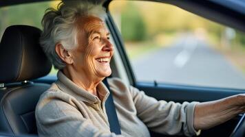 An elderly woman smiles widely while driving down a tree-lined road photo