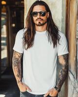 Handsome model in a blank tee poses confidently against a rustic backdrop photo