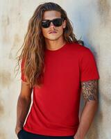 A handsome model with long hair poses confidently in a casual t-shirt photo