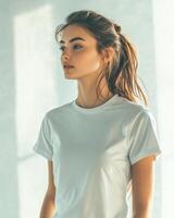 A female model stands gracefully, showcasing a blank white t-shirt in soft light photo