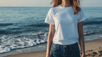 Model poses on the beach in a simple white t-shirt with ocean waves photo