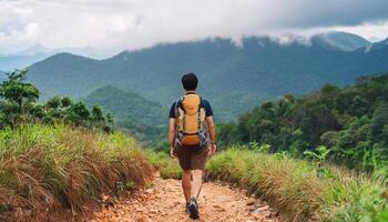 An alone asian man view from behind walking on the path for mountain trekking with beautiful mountain view photo