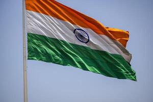 India flag flying high at Connaught Place with pride in blue sky, India flag fluttering, Indian Flag on Independence Day and Republic Day of India, tilt up shot, Waving Indian flag, Har Ghar Tiranga photo
