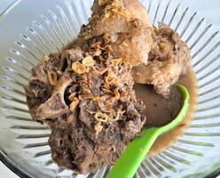Konro soup is a typical Bugis-Makassar food made from beef ribs or bones wrapped in beef cooked with spices, and served warm, a bowl of kondro soup isolated on a wooden press and white BG photo