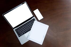 Laptops, tablets and smartphones with blank screens on table, devices are highly used in communication technology these days. photo