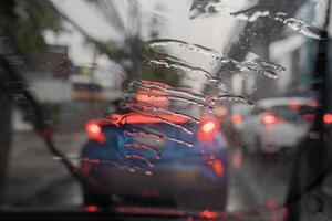 Selective focus to rain droplet with motion blurry wiper on windshield. Motion blurry windshield wipers from inside of car. photo