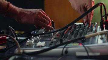Sound engineer adjusting the settings on the mixing console during the daytime music performance, moving knobs and faders with the hands close up video