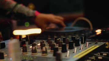 DJ playing music on the controller and changing settings on the mixing console during the live set on the party with a concert light close up video