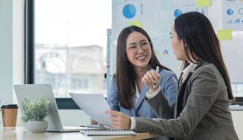 Two Female Accountant Collaborate on Financial Graphs and Data Analysis in a Modern Office Setting photo