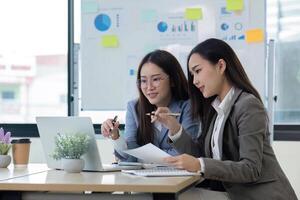 Two Female Accountant Collaborating on Financial Graphs and Data Analysis in a Modern Office Setting photo