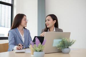 Two Female Accountant Collaborating on Financial Graphs and Data Analysis in a Modern Office Setting photo