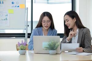 Two Female Accountant Collaborating on Financial Graphs and Data Analysis in a Modern Office Setting photo