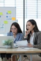 Two Female Accountant Collaborating on Financial Reports in a Modern Office Setting with Charts and Graphs photo