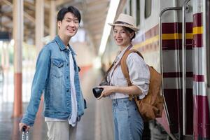 Young Couple Enjoying a Train Trip Together, Smiling and Ready for Adventure with Camera and Luggage at the Train Station photo
