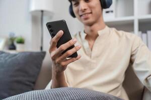 Young Man Relaxing in His Modern Room While Using Smartphone and Listening to Music with Headphones photo