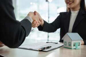Real Estate Agent Shaking Hands with Client Over House Purchase Agreement in Modern Office Setting photo