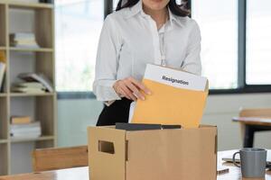 Young Female Office Worker Holding a Box with Resignation Document in a Modern Office Setting photo