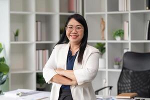 Confident Businesswoman in Modern Office Setting with Arms Crossed, Smiling and Looking at Camera photo