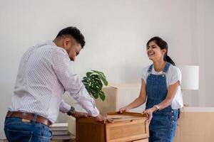 Happy Couple Moving Furniture into Their New Home, Unpacking Boxes and Settling in Together photo