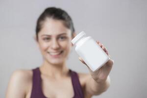 Close-up Of Female Hand Holding Plastic Pill Bottle Containing Vitamins photo