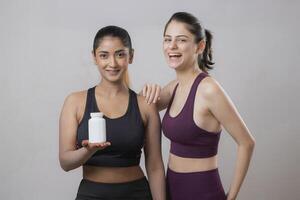 Female Fitness Models Are Smiling And One Model Showing Medicine Bottle photo