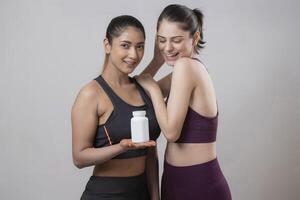 Smiling Beautiful Models Posing For The Camera While One Model Is Displaying Tablet Bottle Holding In Her Hand photo