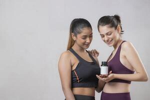 Gym Models Standing Next To Each Other Both Holding A Supplement Bottle In Hands And Looking At It photo