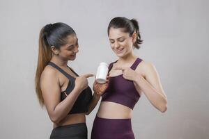 Two Attractive Females Pointing Their Fingers At The Tablet Bottle photo