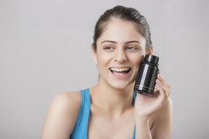 A Close-Up Of A Beautiful Hot Woman Smiling And Showing Her Black Tablet Bottle photo