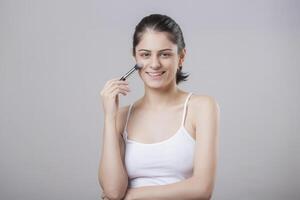 Makeup Model With A Makeup Brush In Her Hand And Her Gaze Fixed On The Front Camera photo