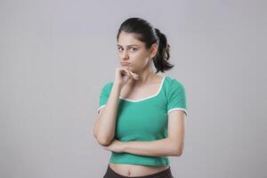 Cute Model Standing With One Hand On Her Chin And Looking At The Camera In Front Of A Grey Background photo