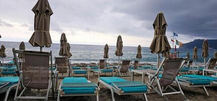 deckchairs and umbrellas on a beach in a seaside resort in Liguria on a cloudy day at the end of summer photo