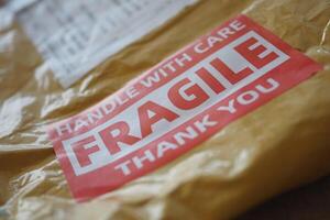 A cardboard box marked with a caution label for fragile goods handling during shipping photo
