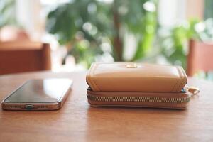 A Stylish Smartphone and a Wallet are Placed on a Beautiful Wooden Table Surface photo