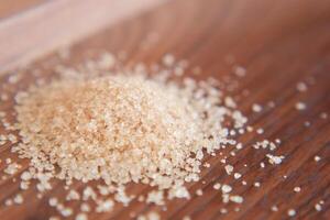 This image features a closeup view of a pile of brown sugar resting on a wooden surface photo